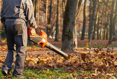 unrecognizable male worker using leaf blower city park fall back view strong man wearing